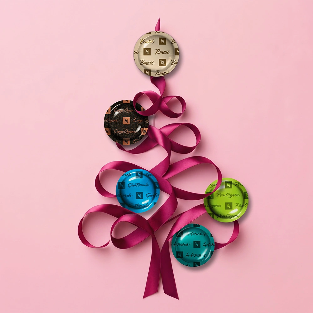 Nespresso Festive: koffiecapsules met roze linten op een roze achtergrond